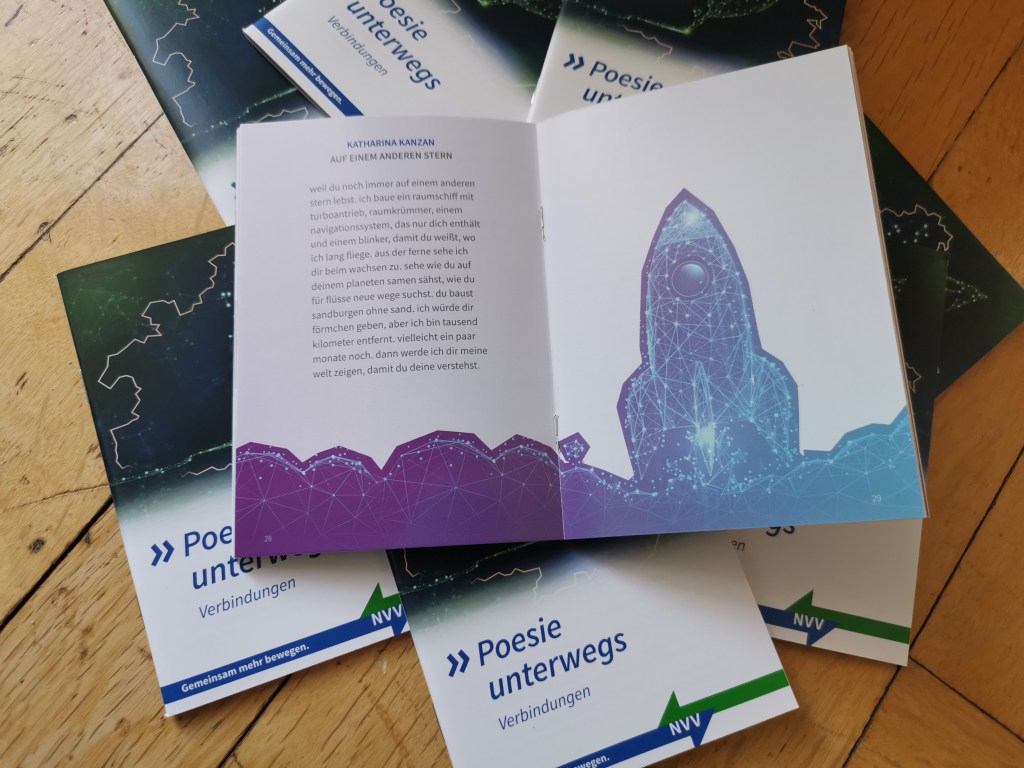 Kleine Hefte mit der Aufschrift "Poesie unterwegs NVV" auf dem Boden verteilt. In der Mitte ein aufgeschlagenes Heft.